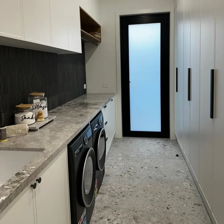 Laundry with stone bench, stacked washer and dryer, and tall cabinets